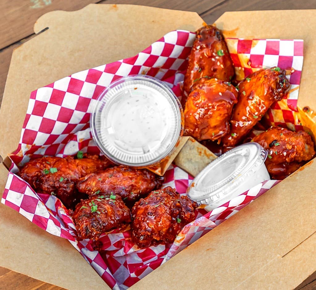 Birdside catering spread with wings, sandos, loaded fries, mac, and drinks.